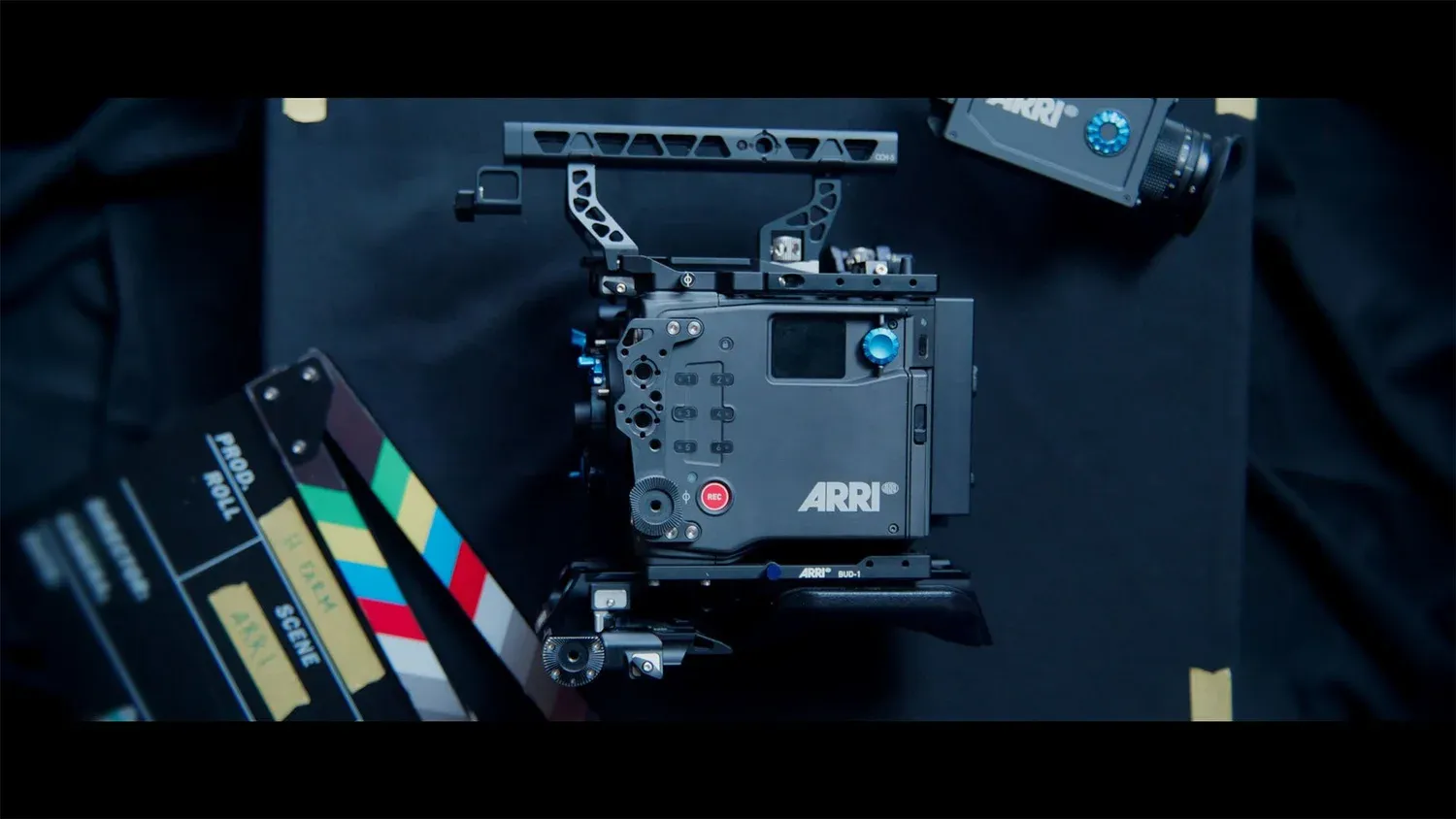 An ARRI cinema camera lying on a dark table next to a clapperboard