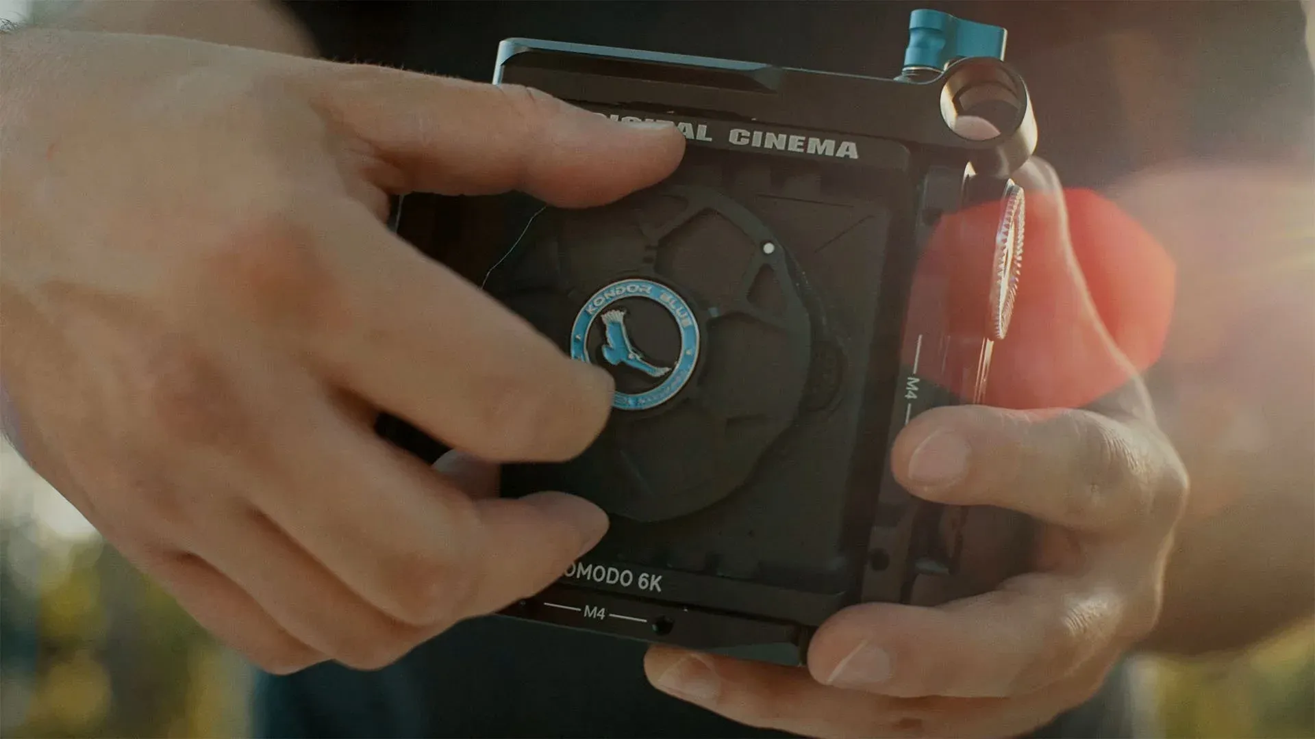 Hands holding the RED Komodo body fitted with the Kondor Blue cage
