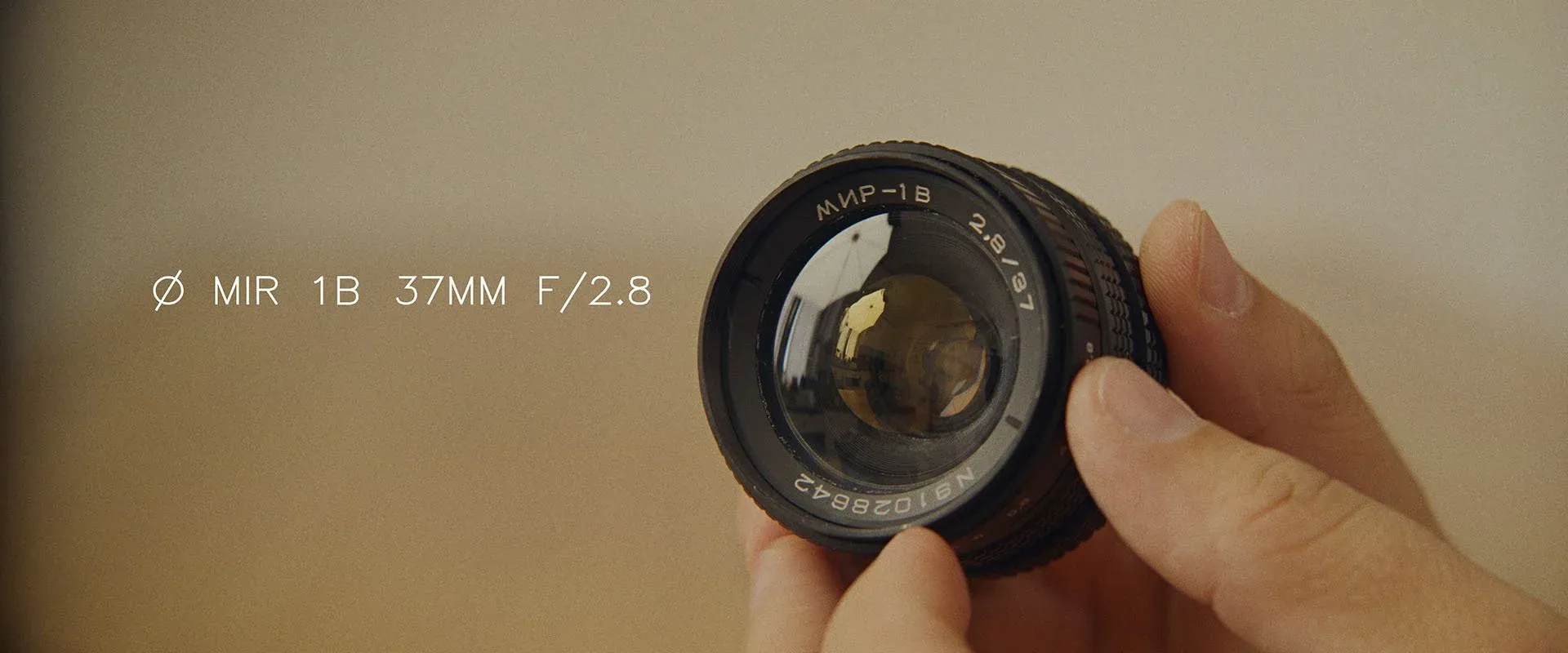 A hand holding the MIR 1B 37mm f/2.8 lens