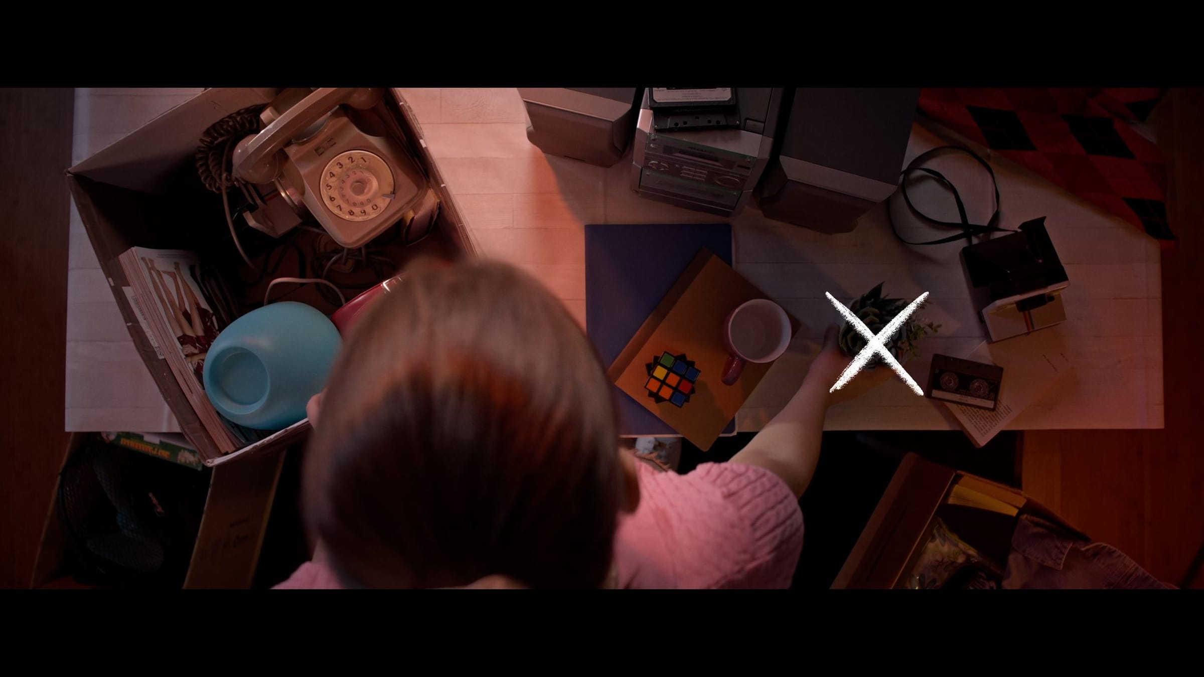 The same girl placing the plant on the right side of the table, a cross marking the action