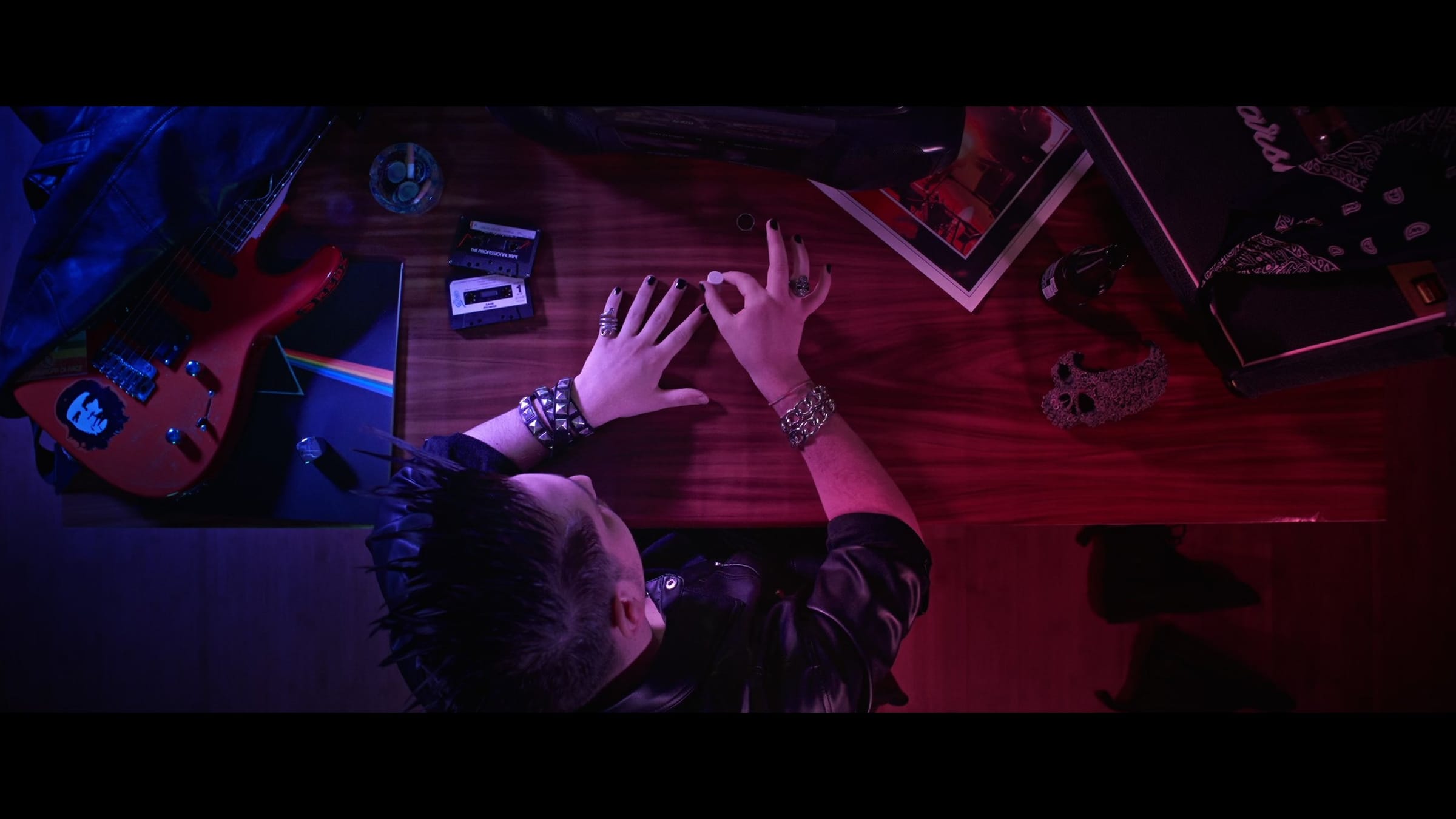 Overhead shot of hands with rings resting on a desk, lit in magenta and blue